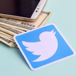 Twitter logo next to dollars and smartphone